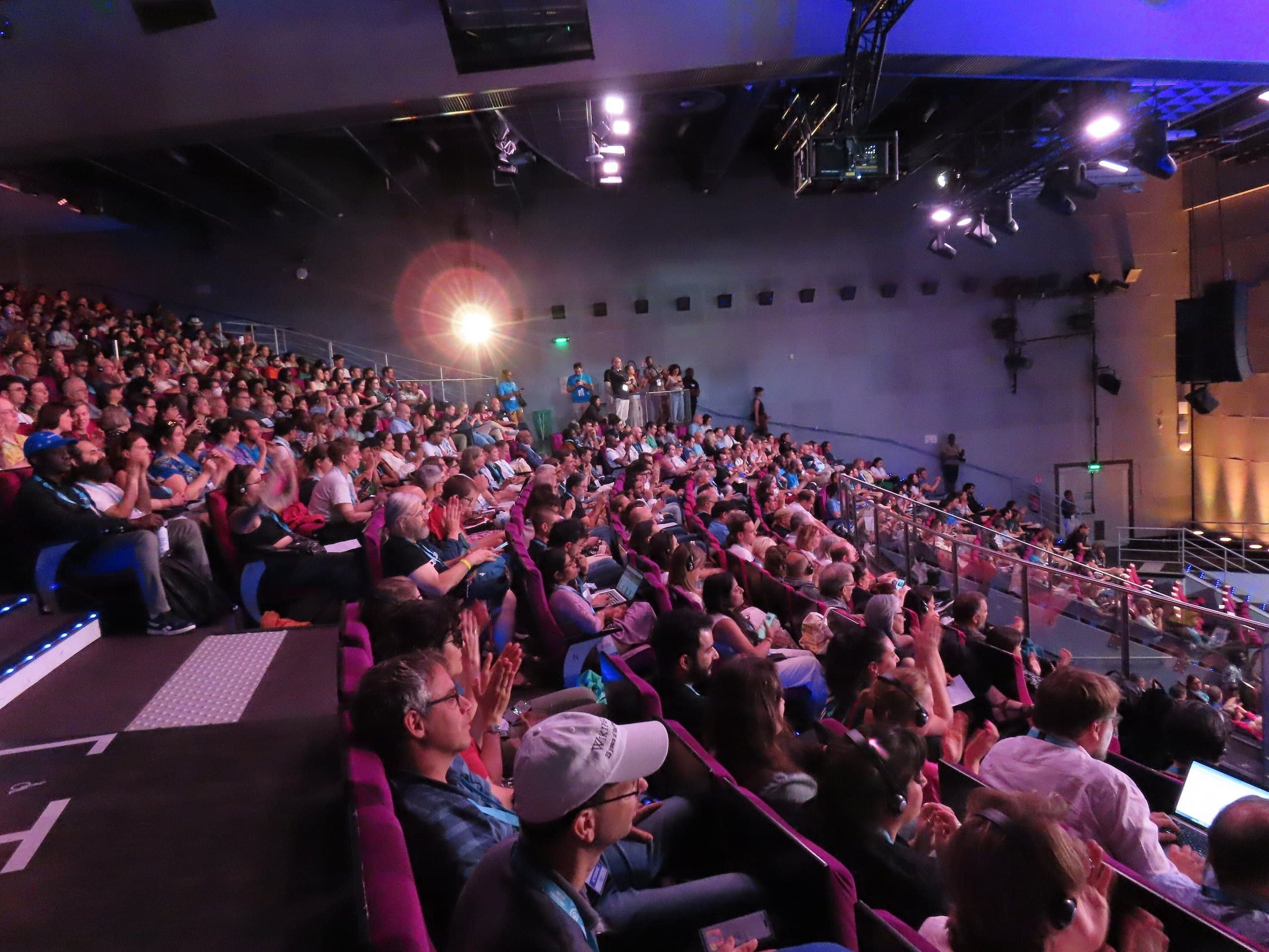 Auditório cheio com luzes de palco, antes de uma palestra