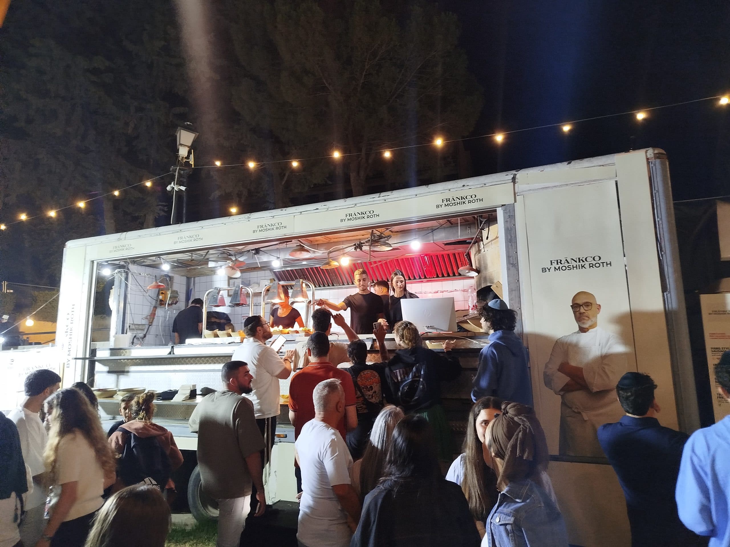 Food truck iluminado à noite com público